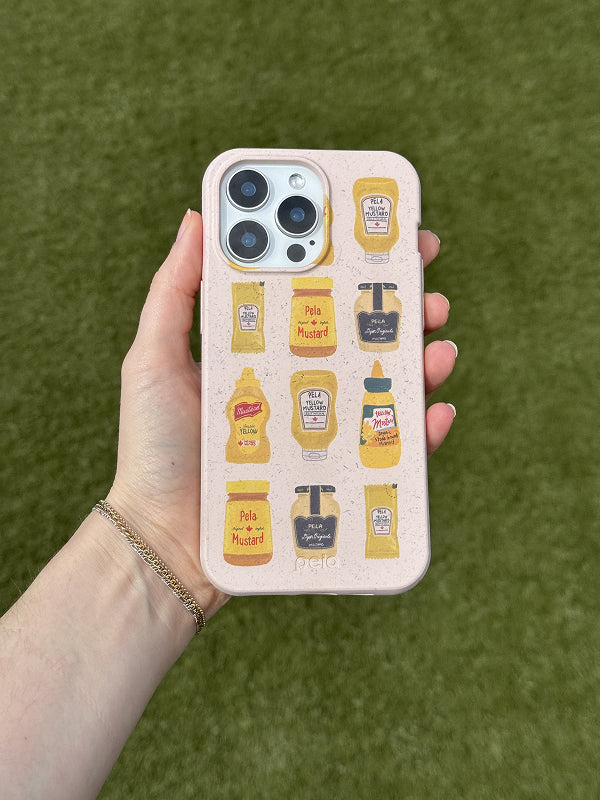 A hand holds a Pela phone case featuring the Mustard Fan design. The case has a light speckled beige background decorated with various illustrated mustard bottles and jars, including classic yellow mustard, Dijon, and spicy varieties—all labeled with playful text like 