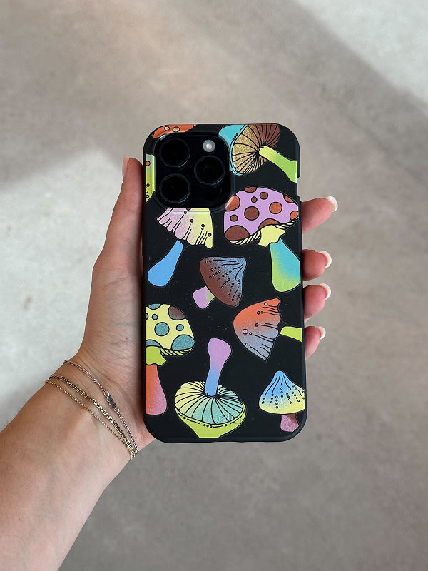 A hand holding the Pela “Mushroom Party” Phone Case featuring colorful, neon mushrooms on a black background.